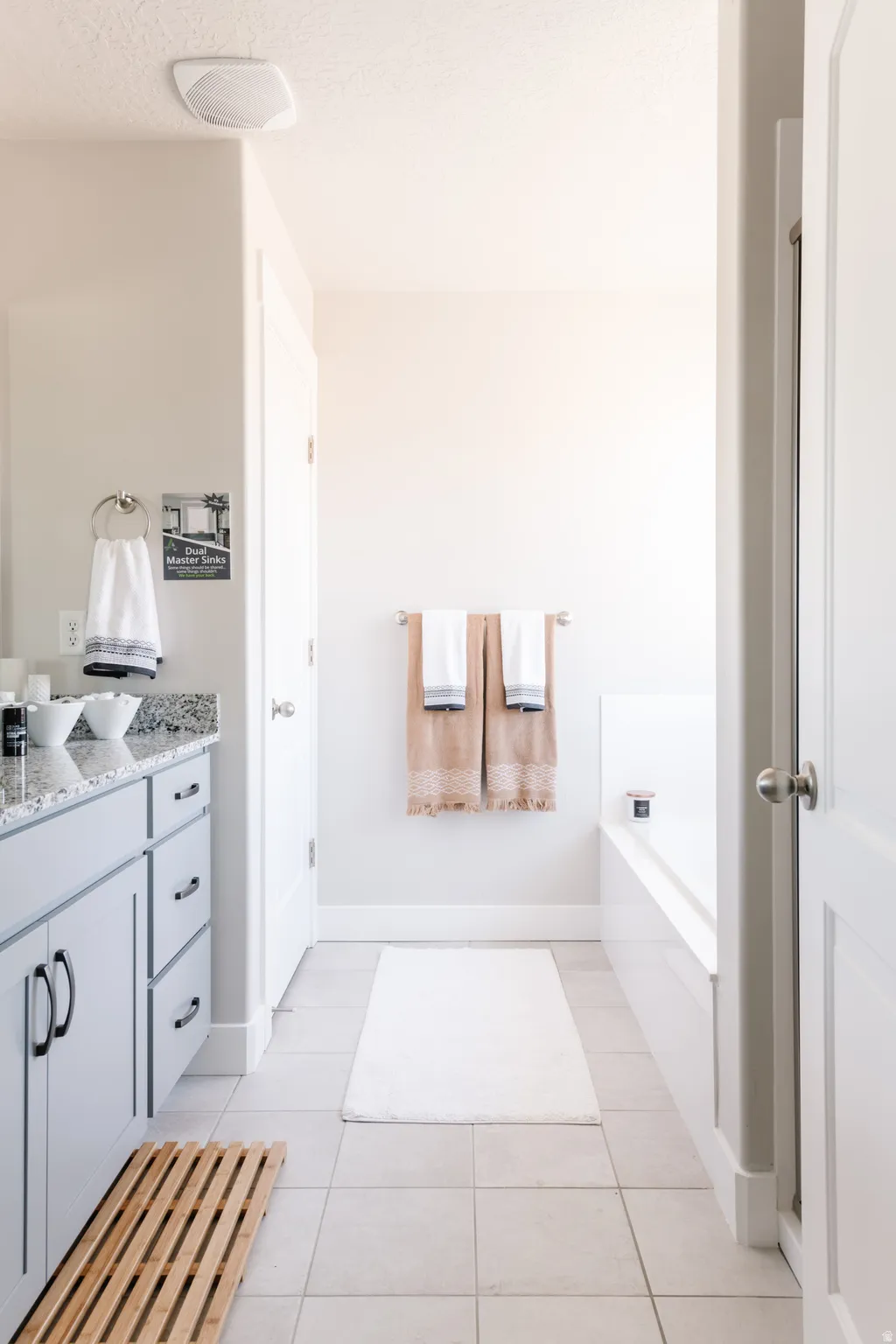 Bathroom with vanity, a garden tub, light tile patterned floors, and a textured ceiling