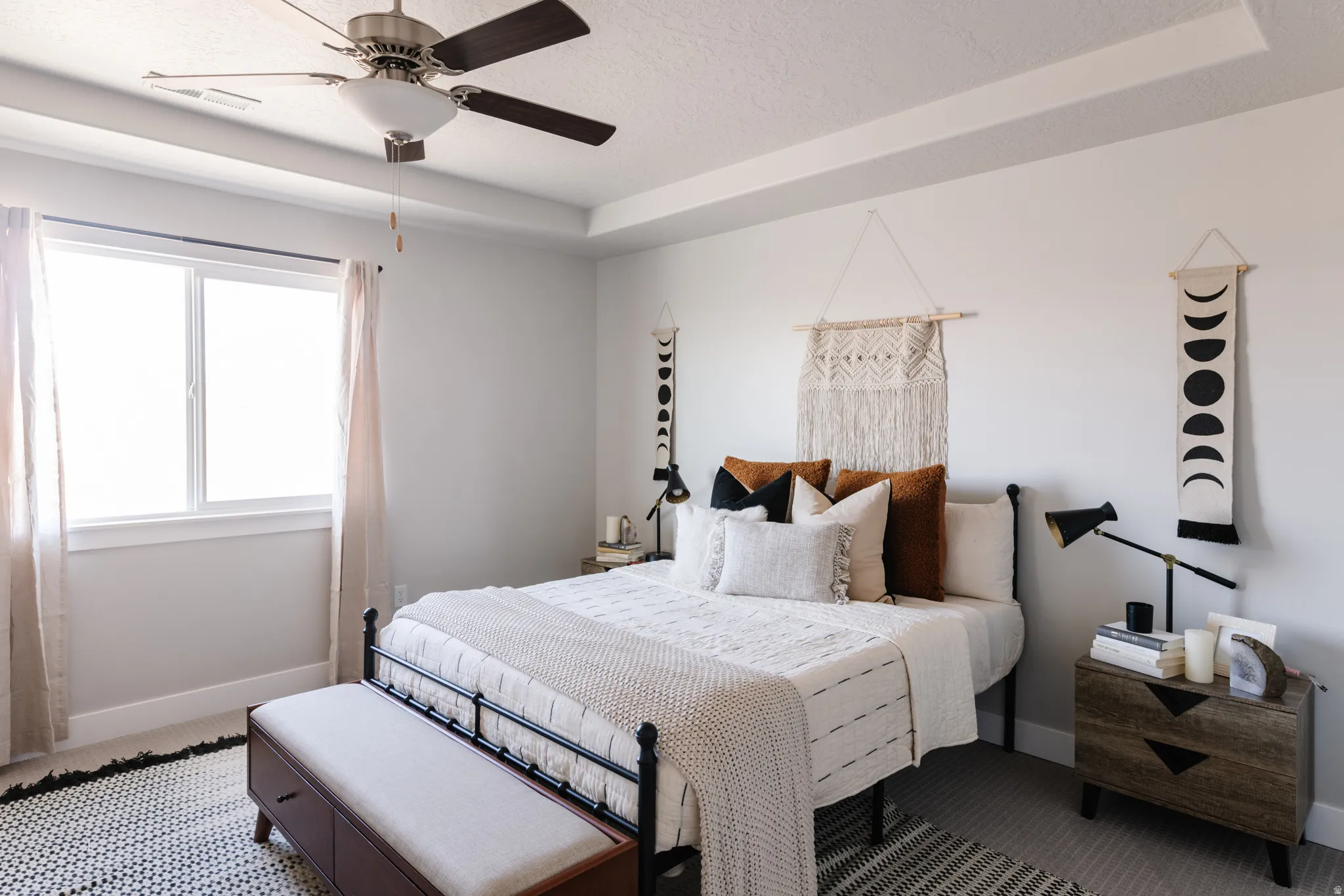 Bedroom with a textured ceiling, a tray ceiling, and a ceiling fan