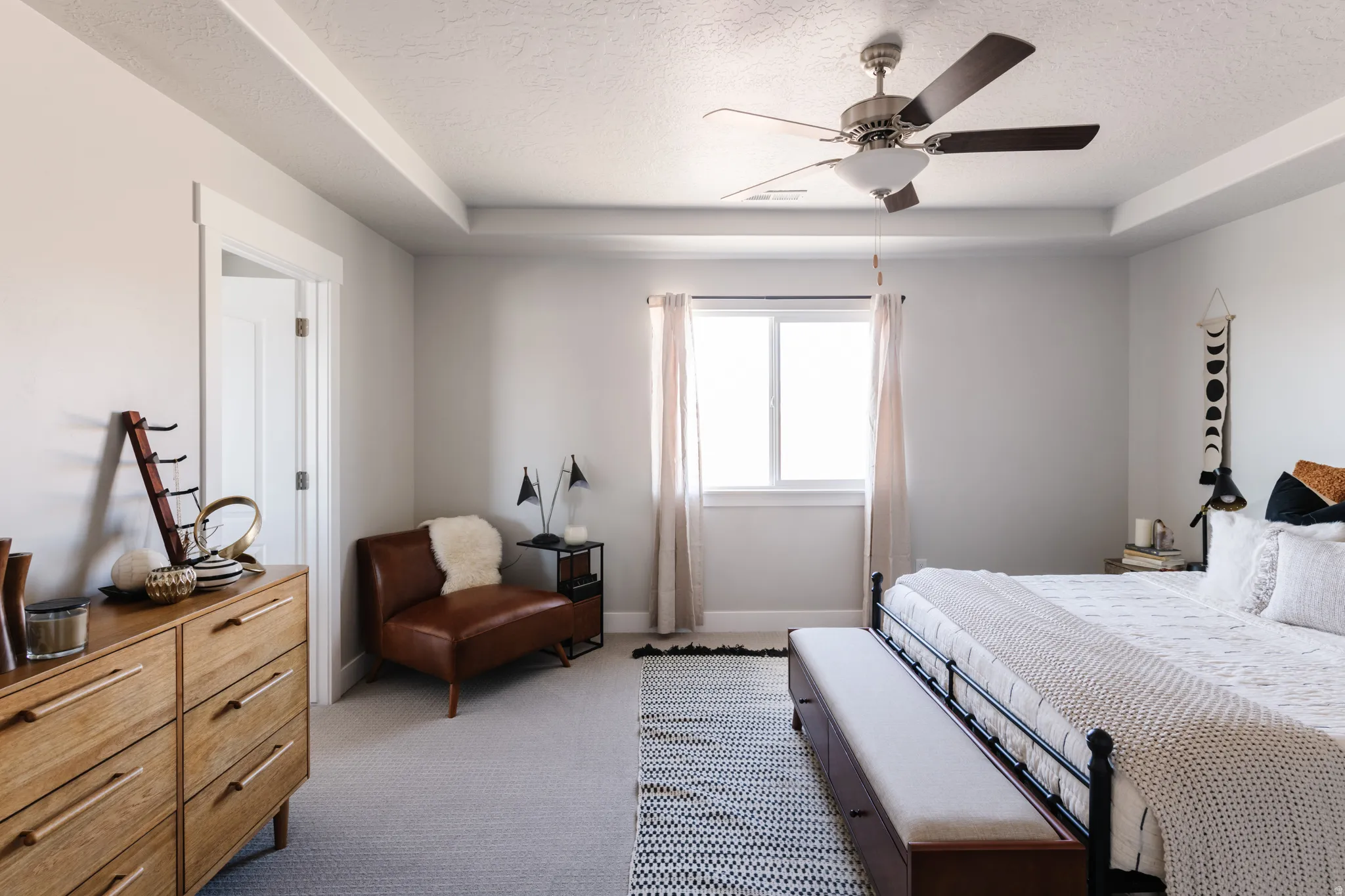 Bedroom with a raised ceiling, a textured ceiling, carpet, and ceiling fan