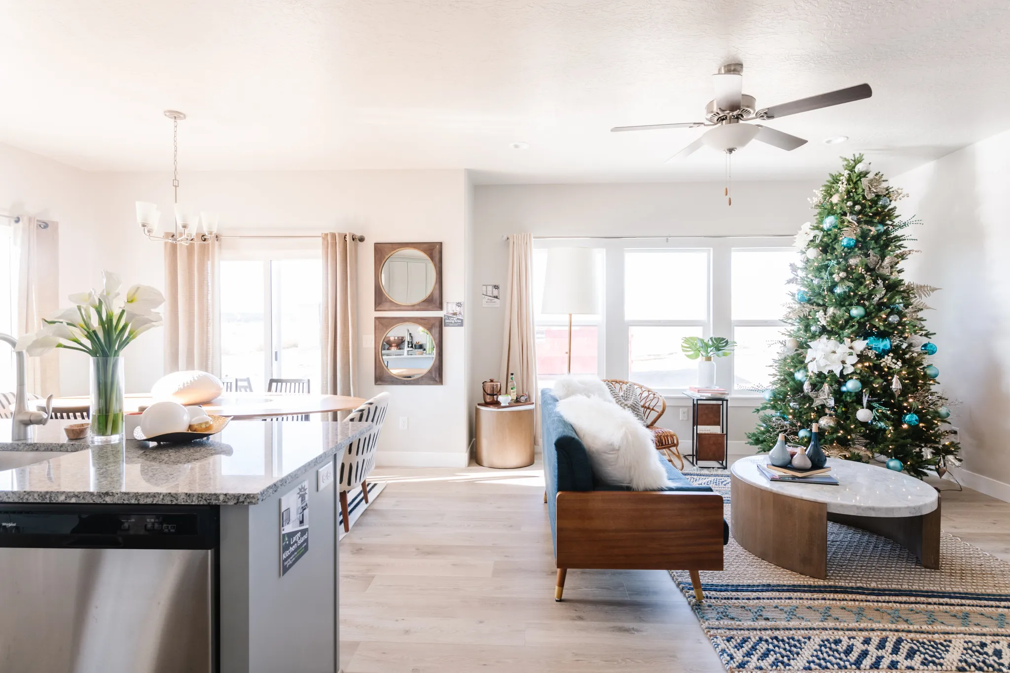 Living room with light wood finished floors, ceiling fan, and suspended lighting