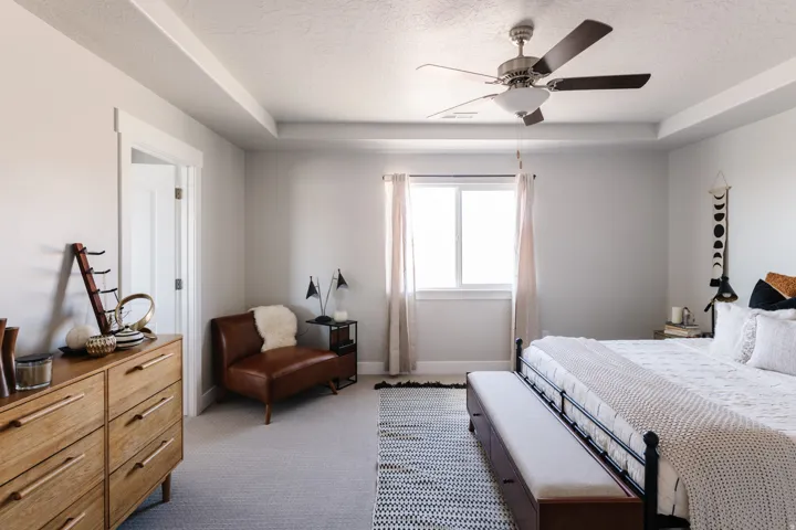 Bedroom with a raised ceiling, a textured ceiling, carpet, and ceiling fan