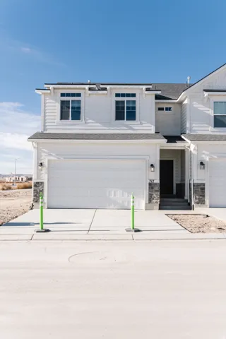 Traditional-style house featuring a garage, concrete driveway, and stone siding