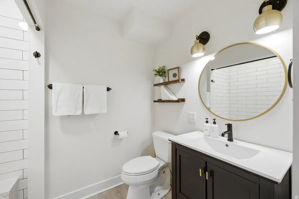 Full bath with vanity, light wood-style flooring, and a shower