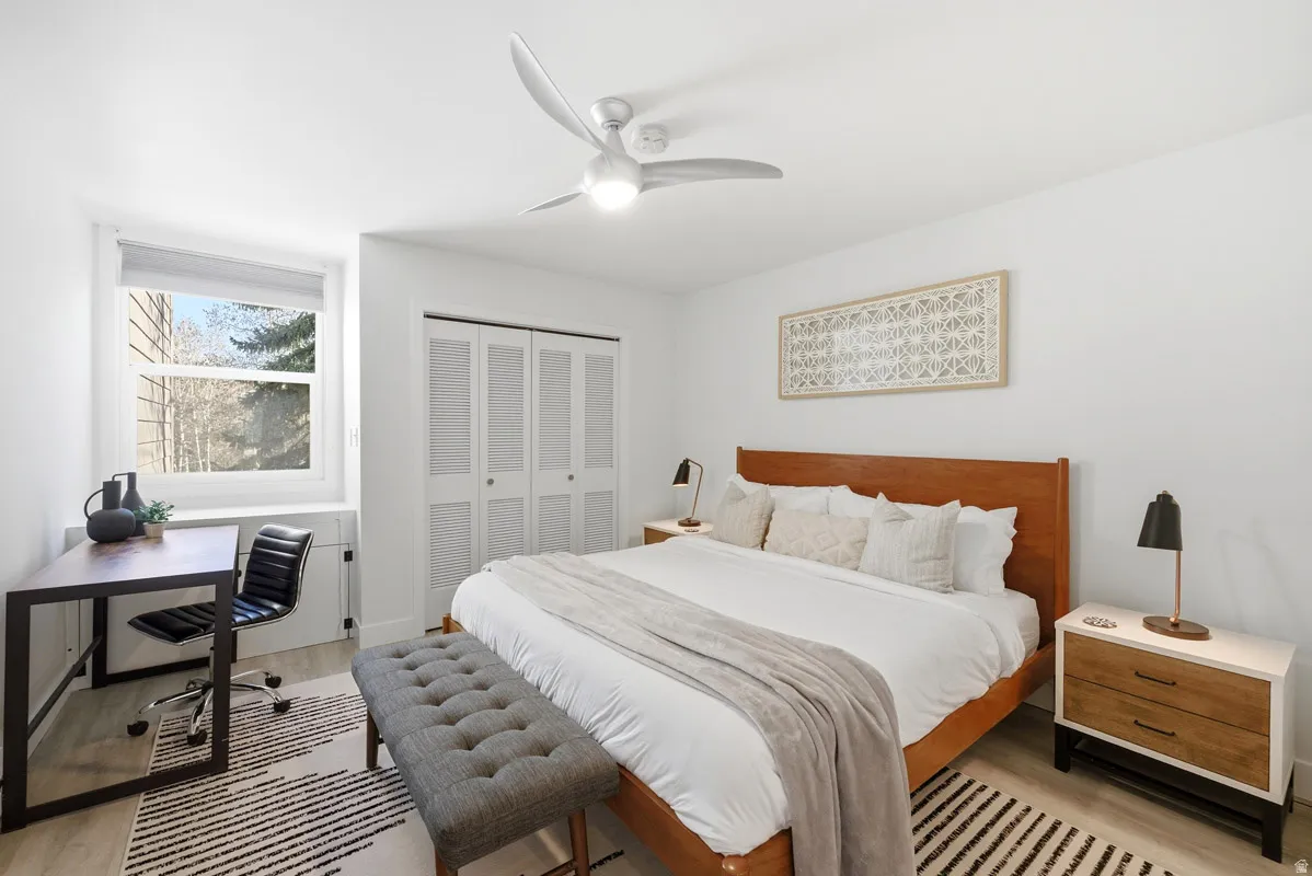 Bedroom featuring light wood-style floors, a desk, a closet, and a ceiling fan