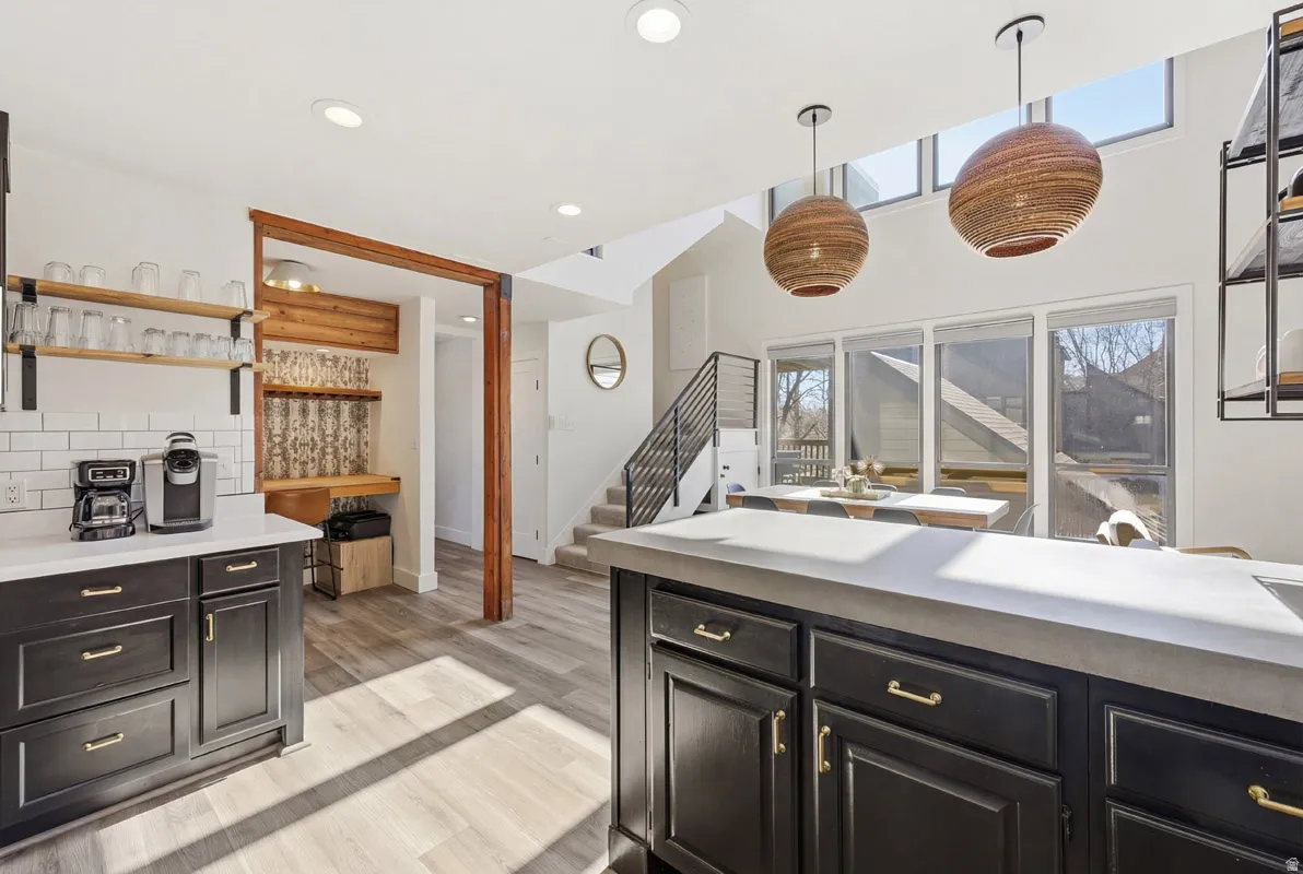 Kitchen with healthy amount of natural light, light countertops, light wood-style floors, and dark cabinetry