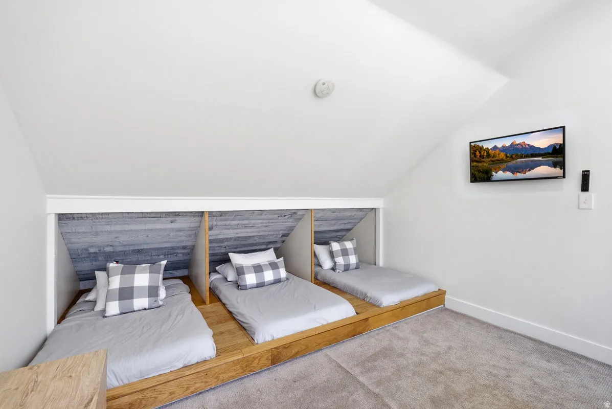 Carpeted bedroom featuring lofted ceiling and baseboards