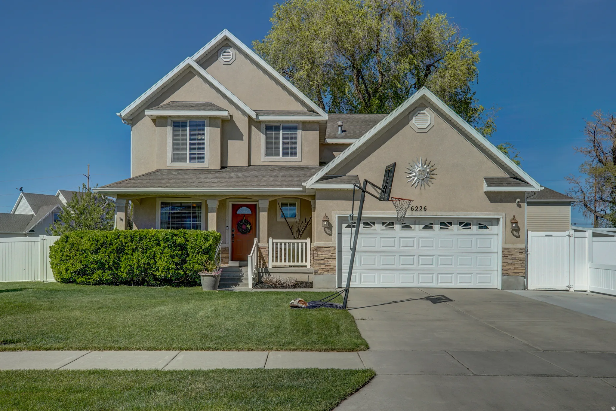 View of front of house featuring stucco siding, a porch, driveway, stone siding, and a shingled roof