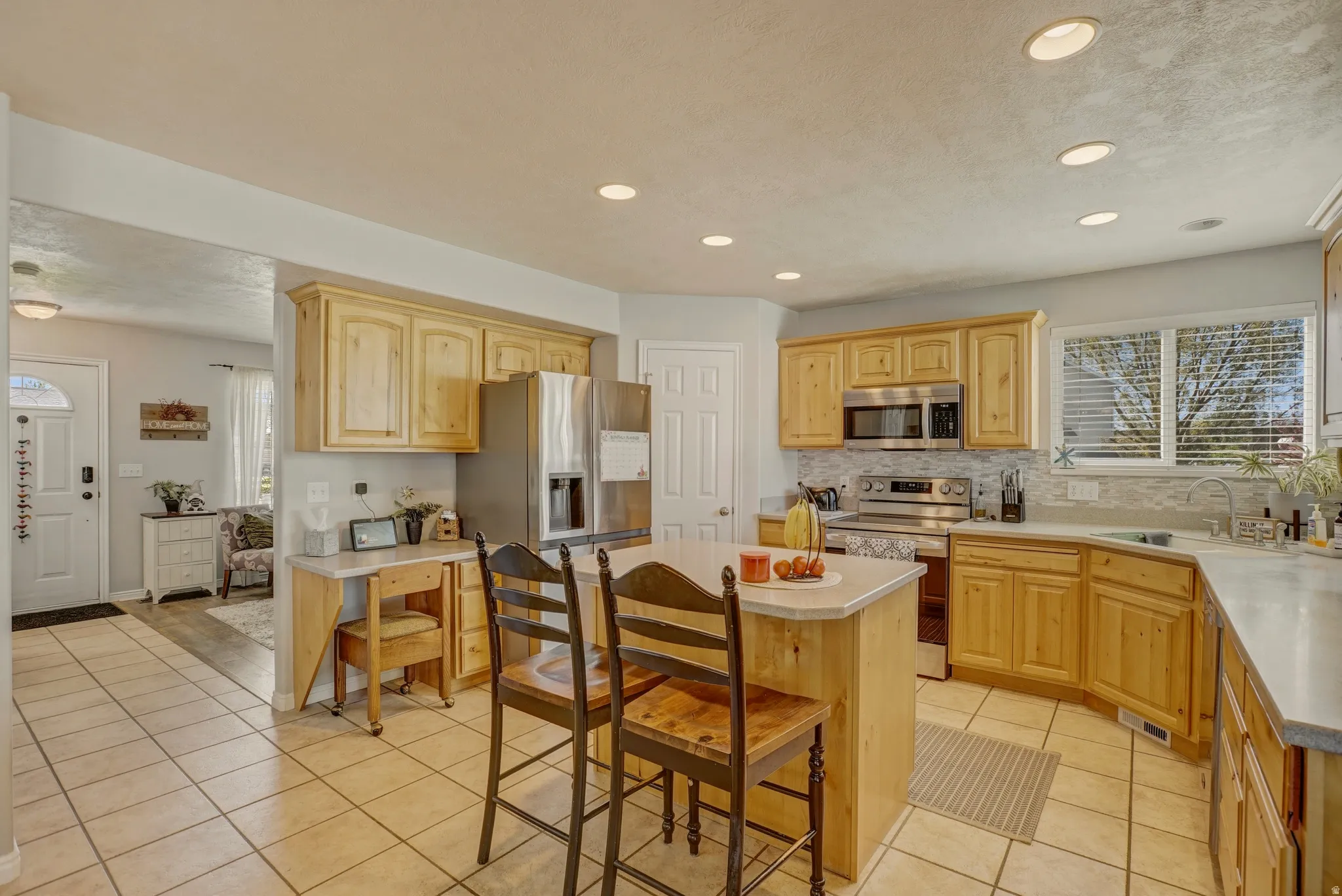 Kitchen with stainless steel appliances, light wood finish cabinetry, light tile patterned floors, light countertops, and recessed lighting