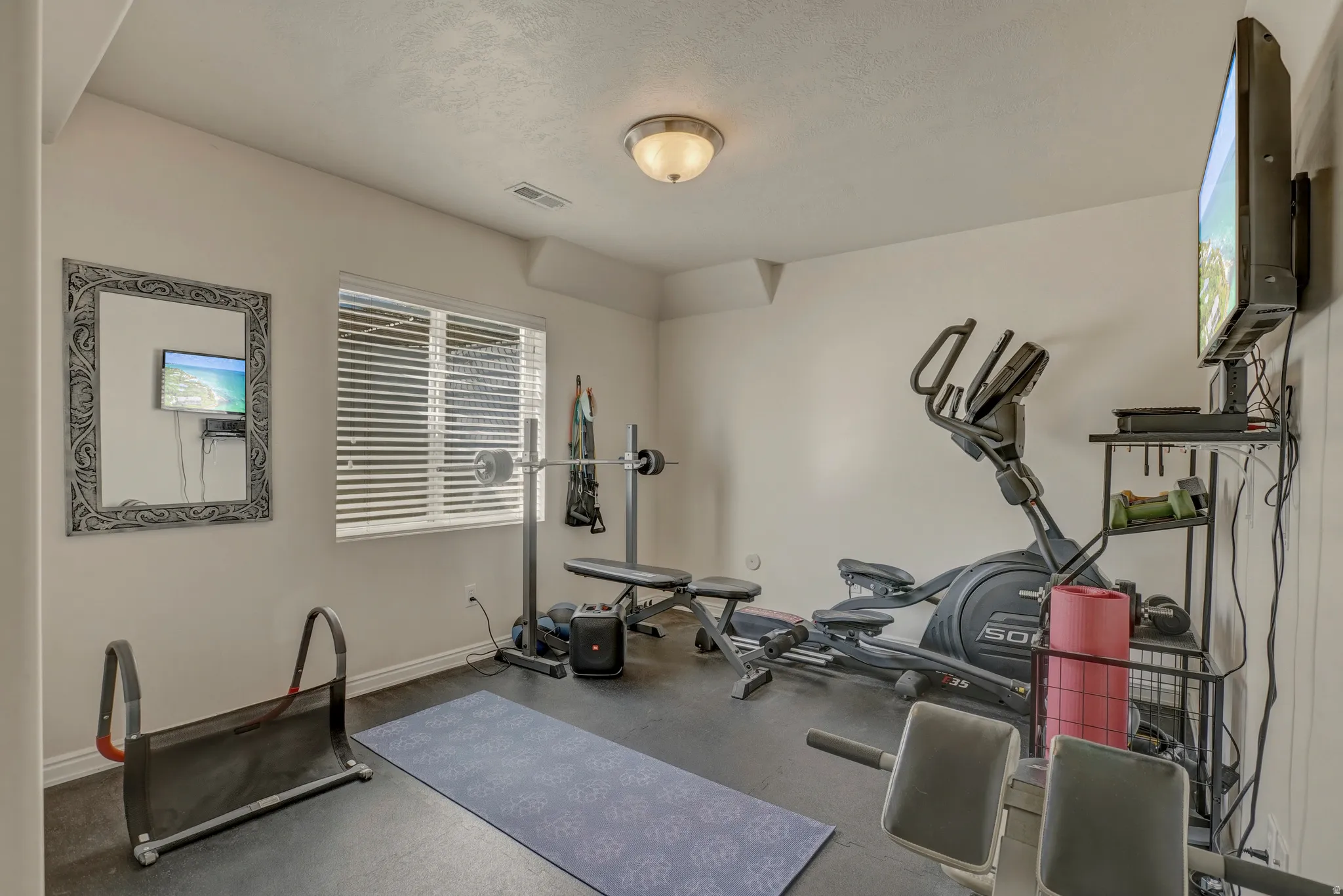 Exercise area featuring dark flooring and a textured ceiling