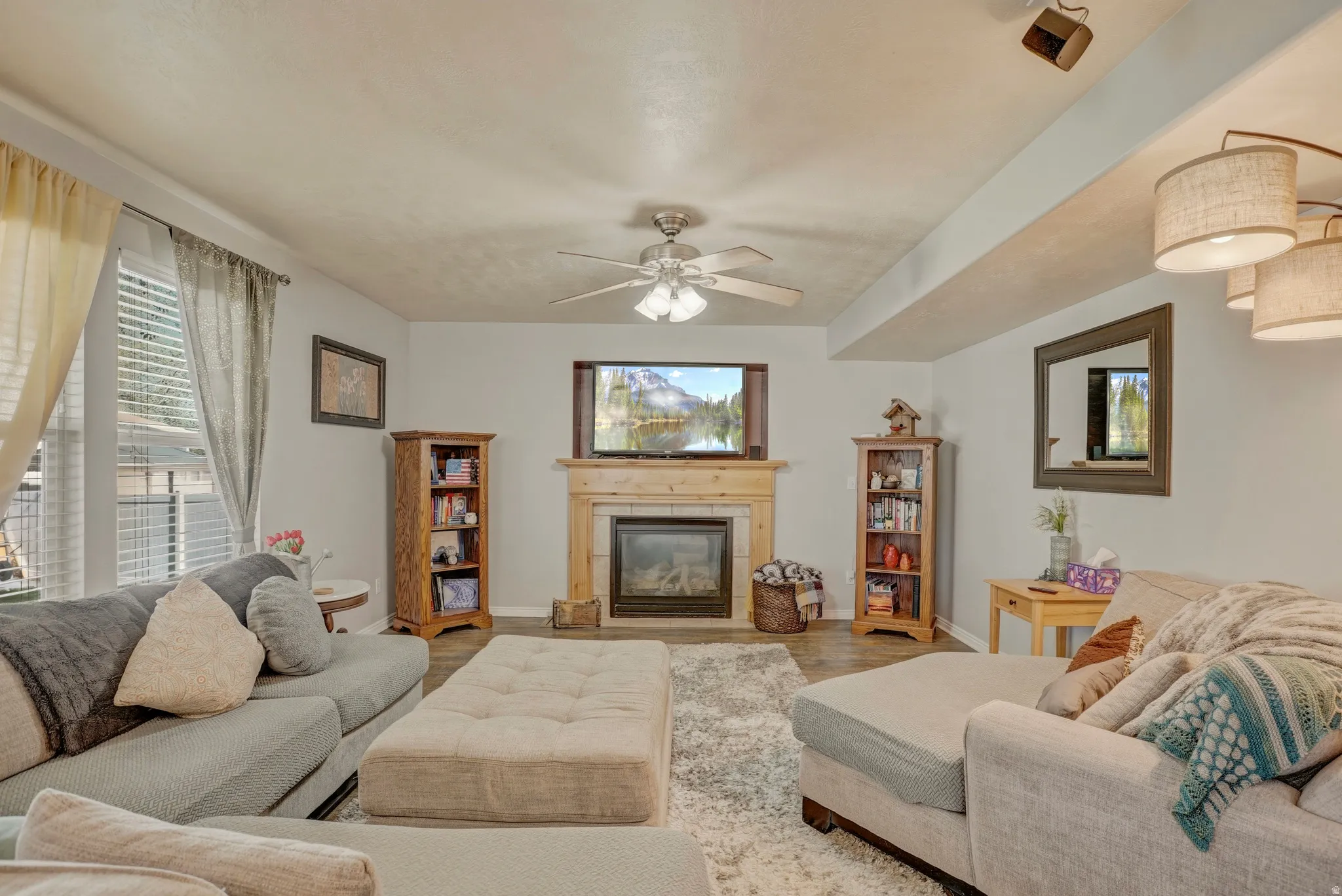 Living room featuring ceiling fan, wood finished floors, and a tile fireplace