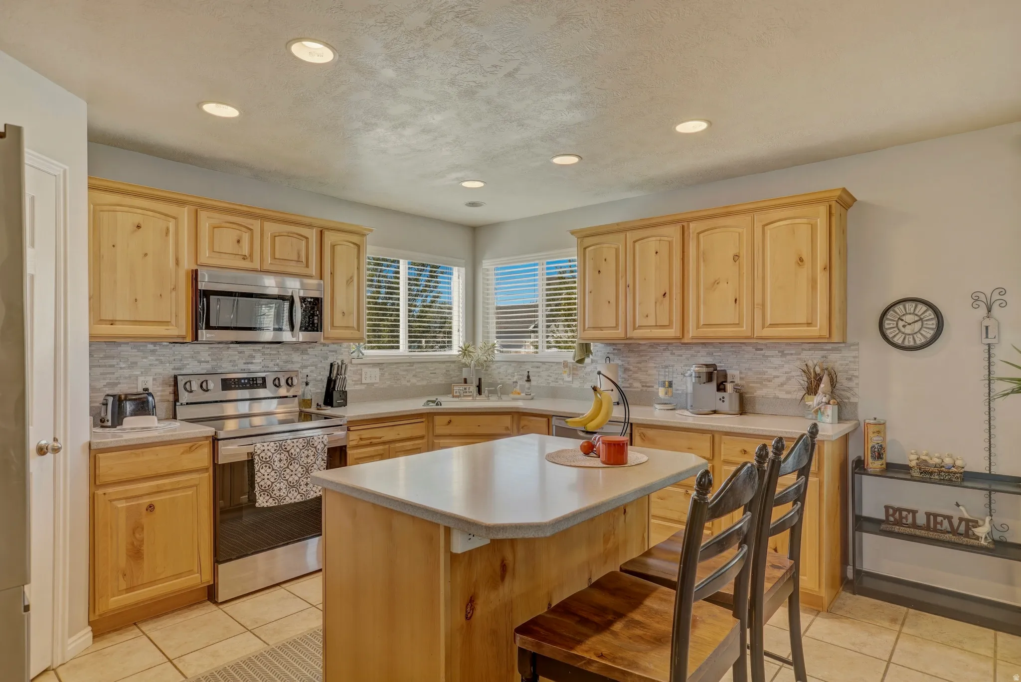 Kitchen featuring light wood finish cabinetry, stainless steel appliances, light countertops, light tile patterned floors, and recessed lighting