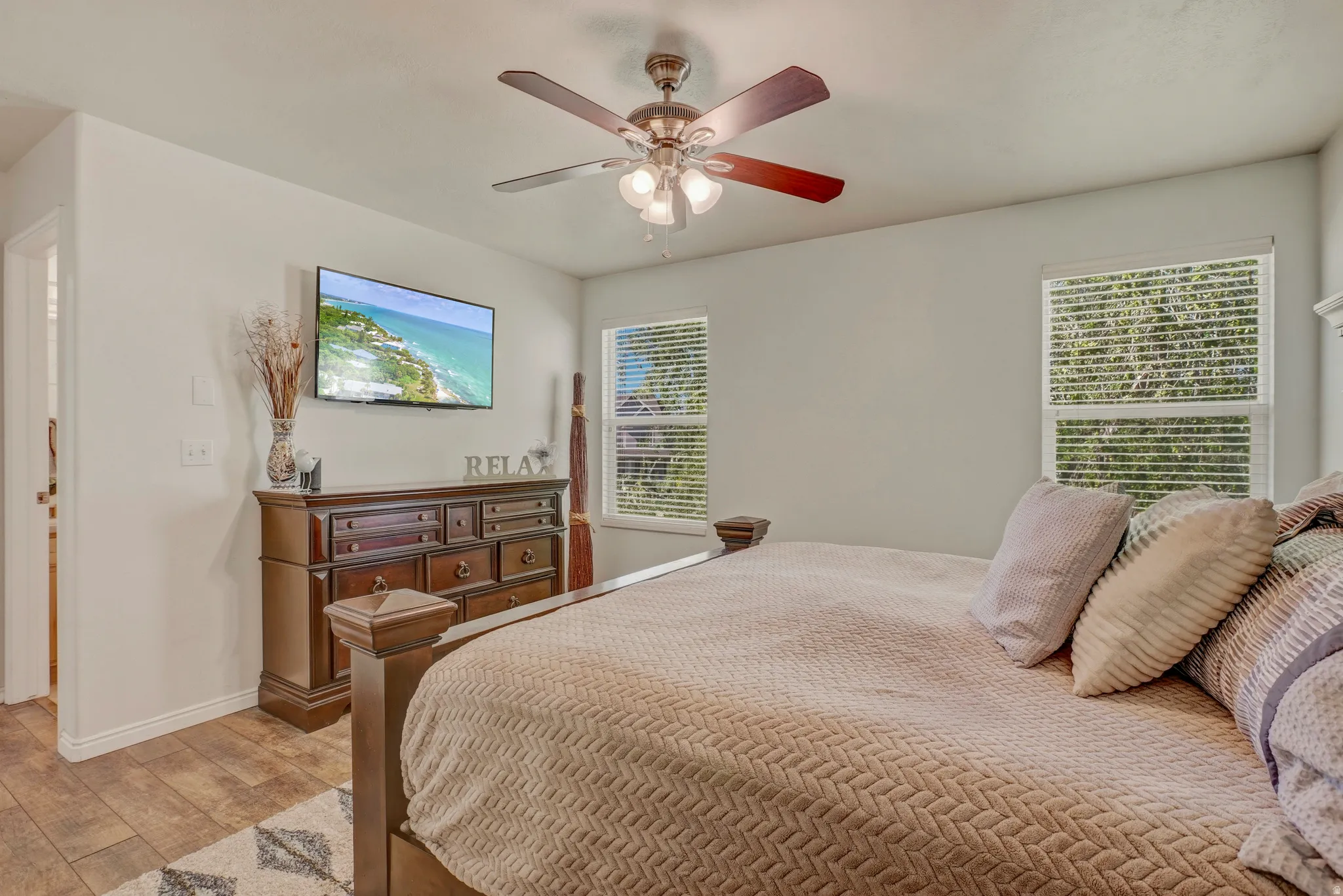 Bedroom with wood finished floors, multiple windows, and a ceiling fan
