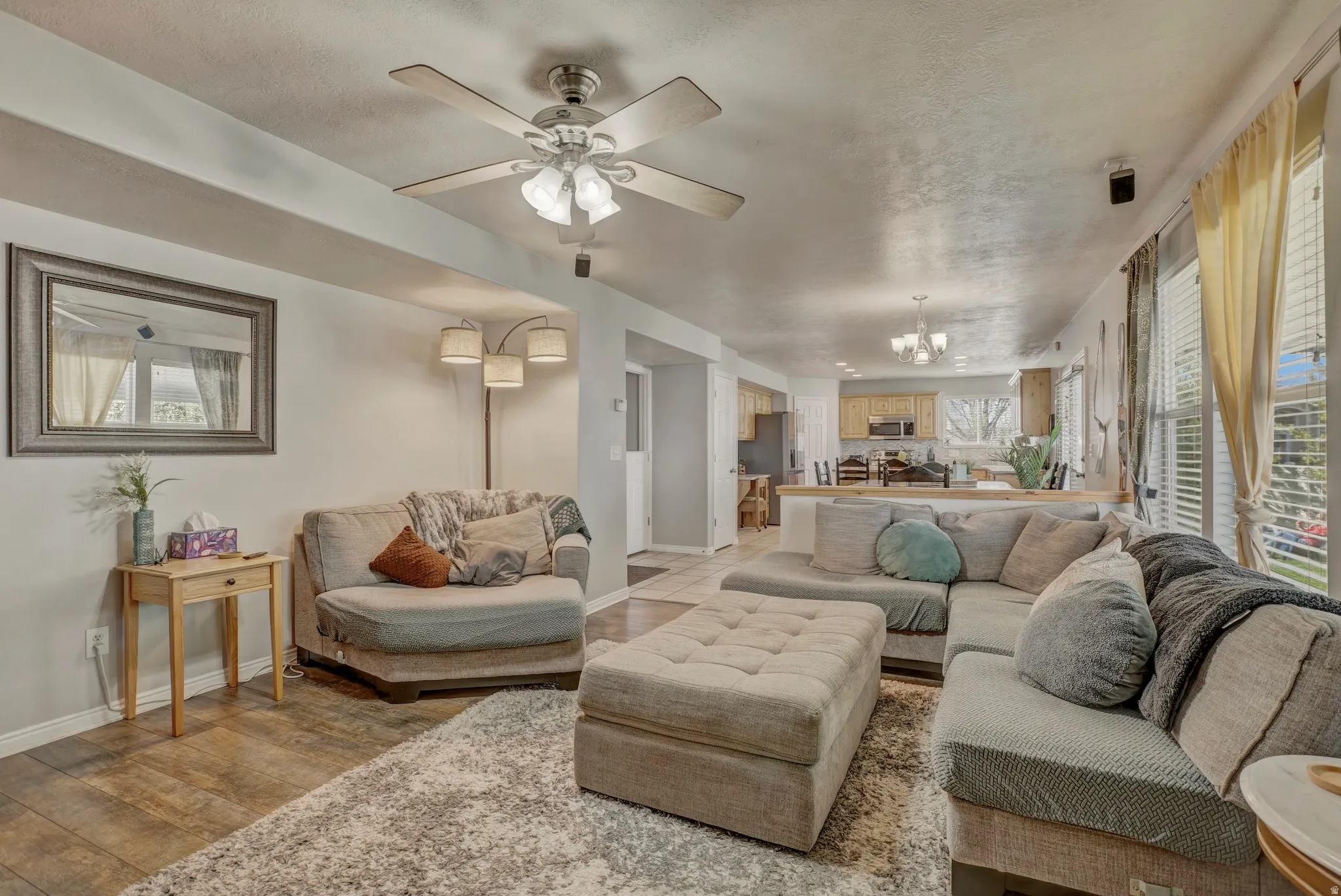 Living room with hanging lights, a ceiling fan, plenty of natural light, and light wood-style floors