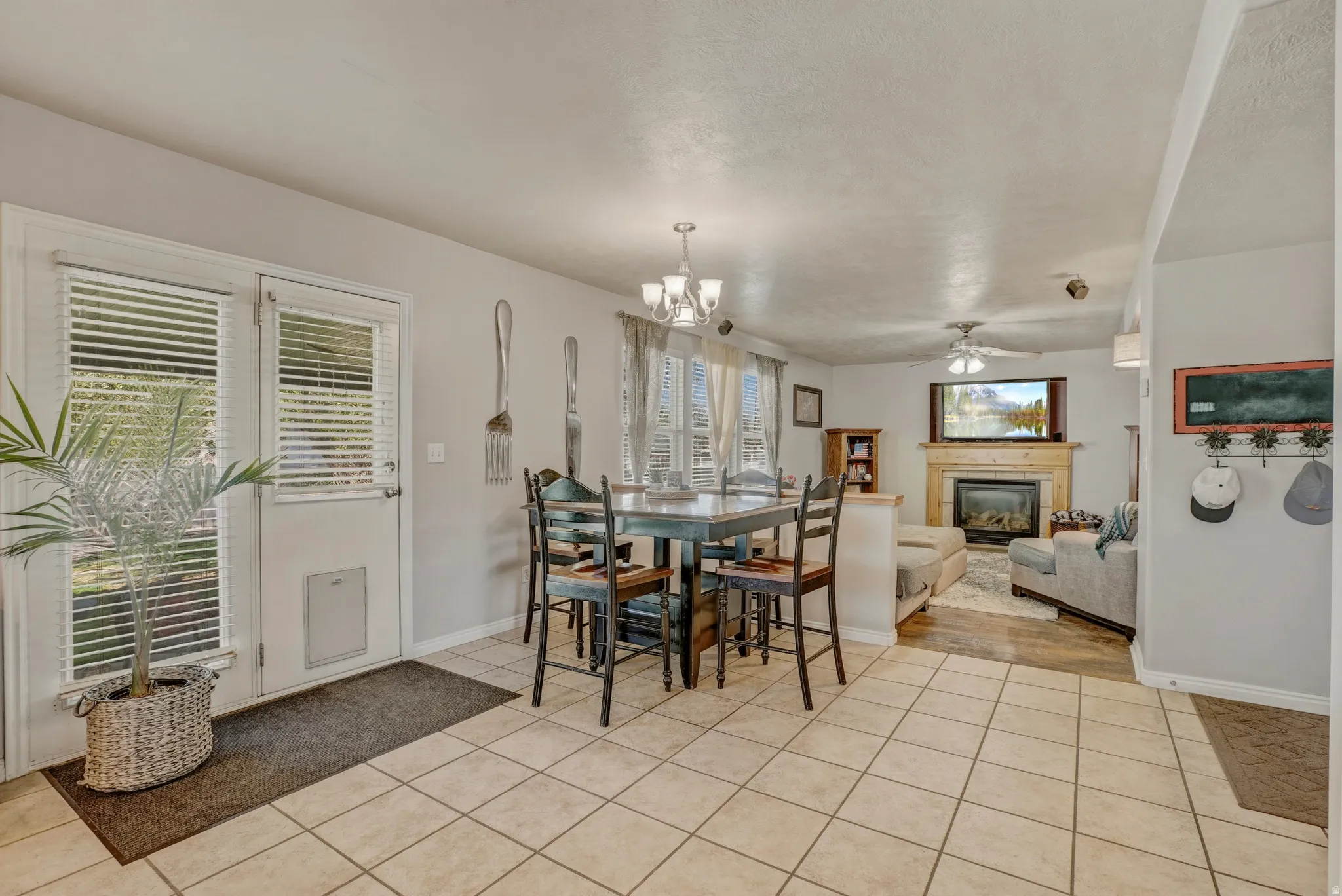 Dining area featuring a glass covered fireplace, light tile patterned flooring, ceiling fan, suspended lighting, and plenty of natural light