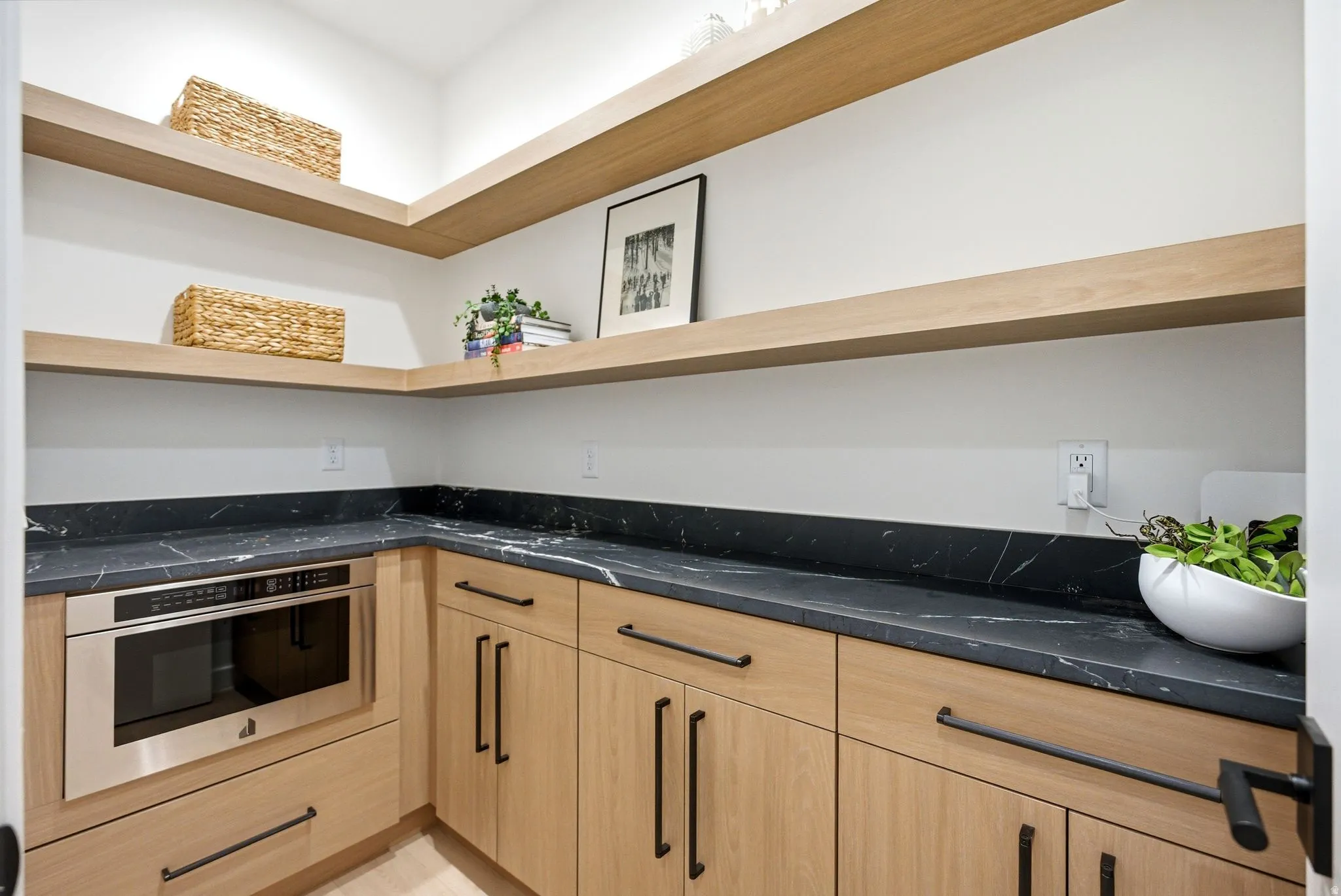 Kitchen featuring oven, light wood finish cabinets, dark stone counters, open shelves, and modern cabinets