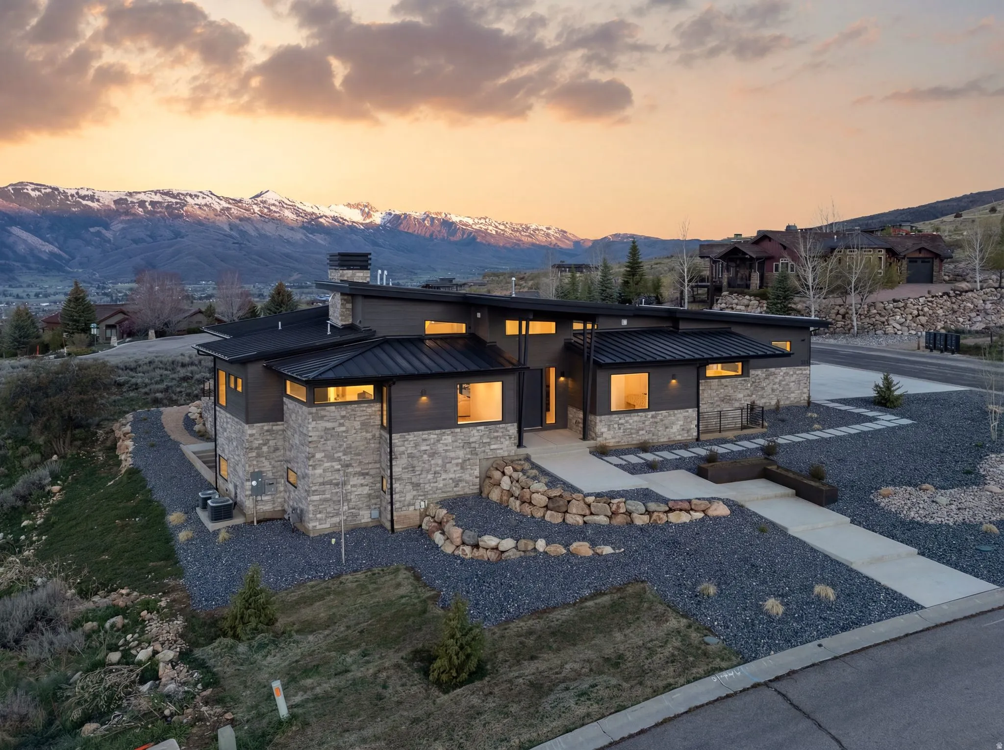 Contemporary house featuring stone siding, a standing seam roof, a mountain view, and a chimney