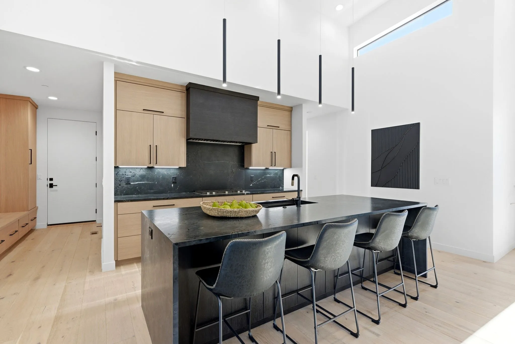 Kitchen featuring light wood finish cabinets, modern cabinets, dark stone counters, light wood-style flooring, and a breakfast bar