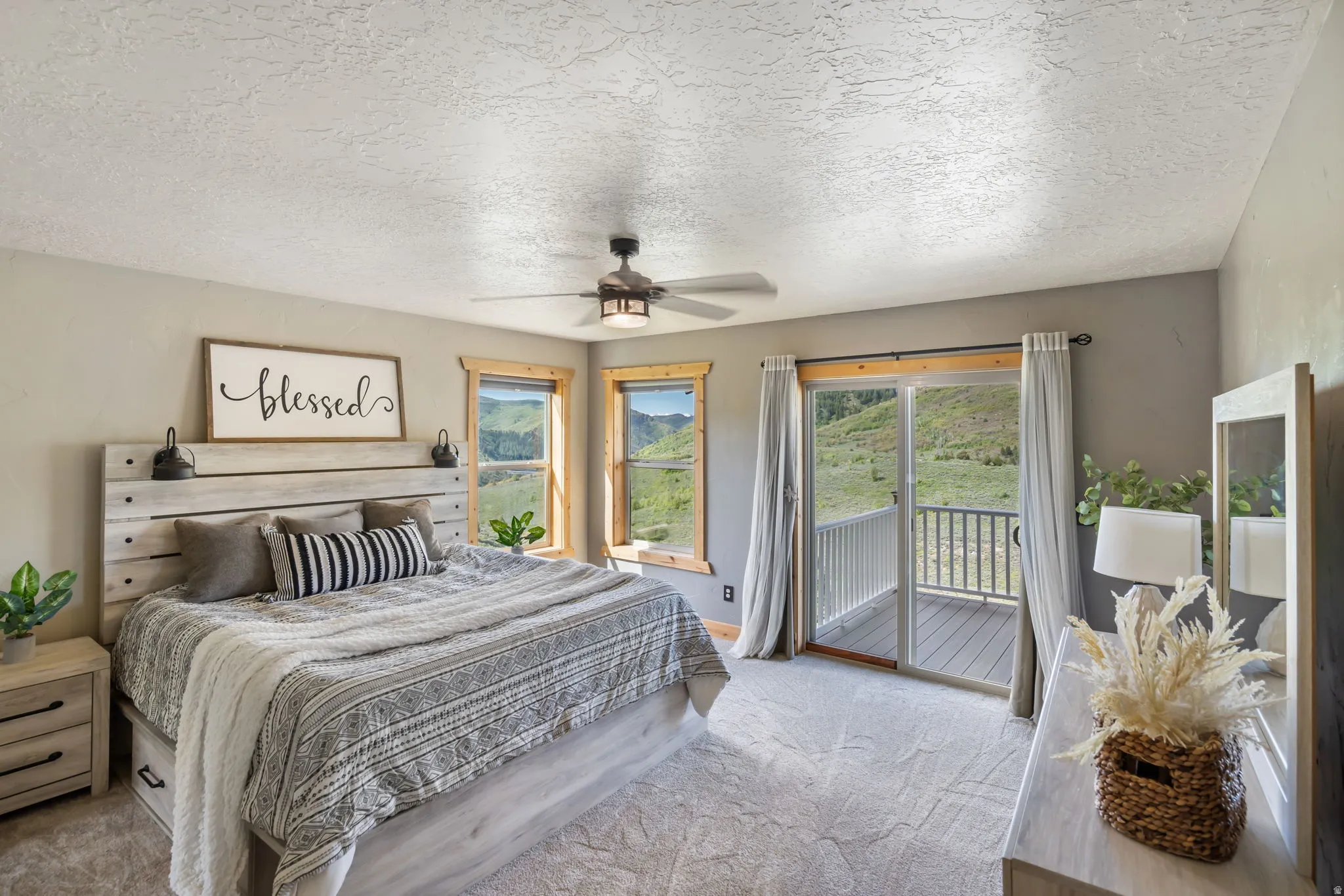 Bedroom featuring a textured ceiling, light colored carpet, access to exterior, and a ceiling fan
