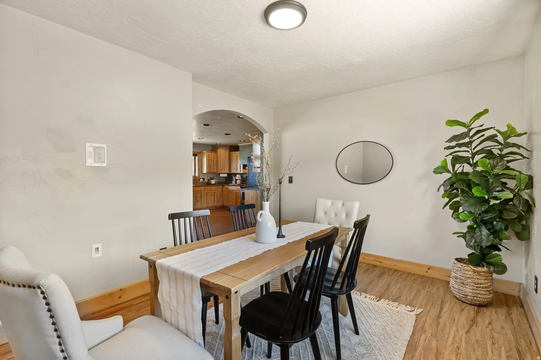 Dining space featuring arched walkways and light wood-style flooring