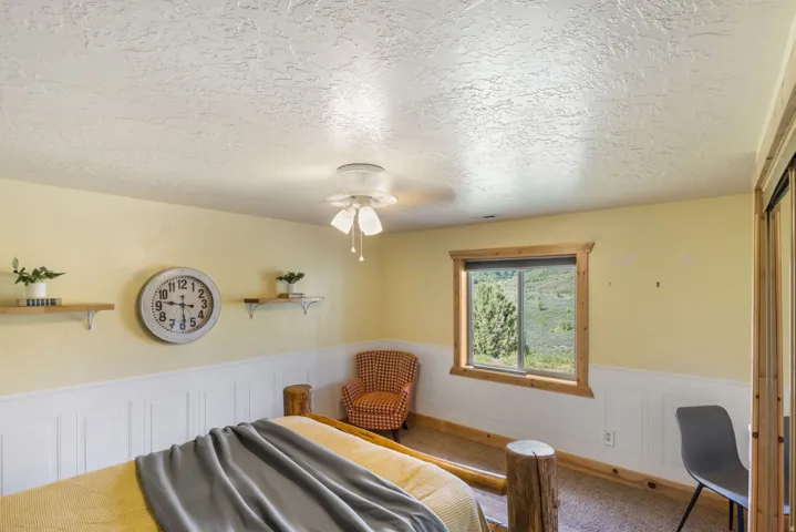 Bedroom with a wainscoted wall, a decorative wall, a textured ceiling, and carpet