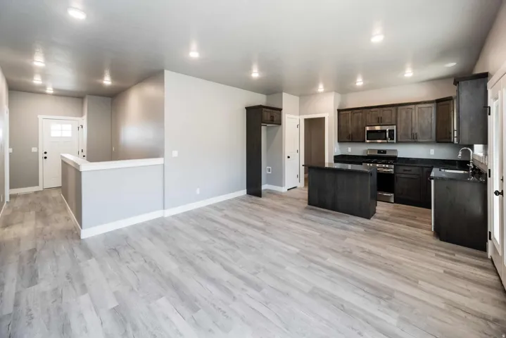 Kitchen with a kitchen island, stainless steel appliances, dark wood finish cabinets, recessed lighting, and light wood-style floors