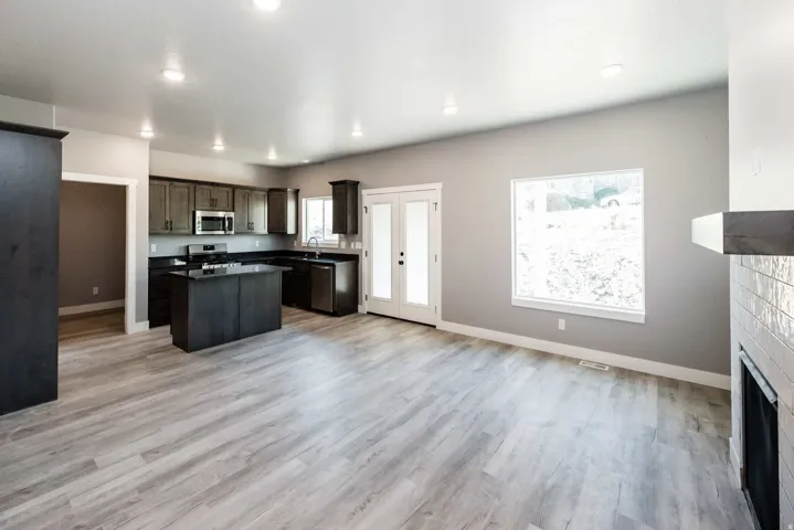 Kitchen with a kitchen island, dark wood finish cabinetry, open floor plan, stainless steel appliances, and dark countertops