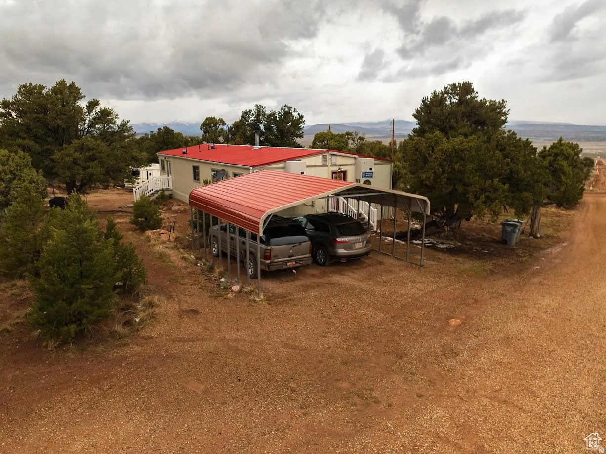 View of front facade featuring a carport and dirt driveway