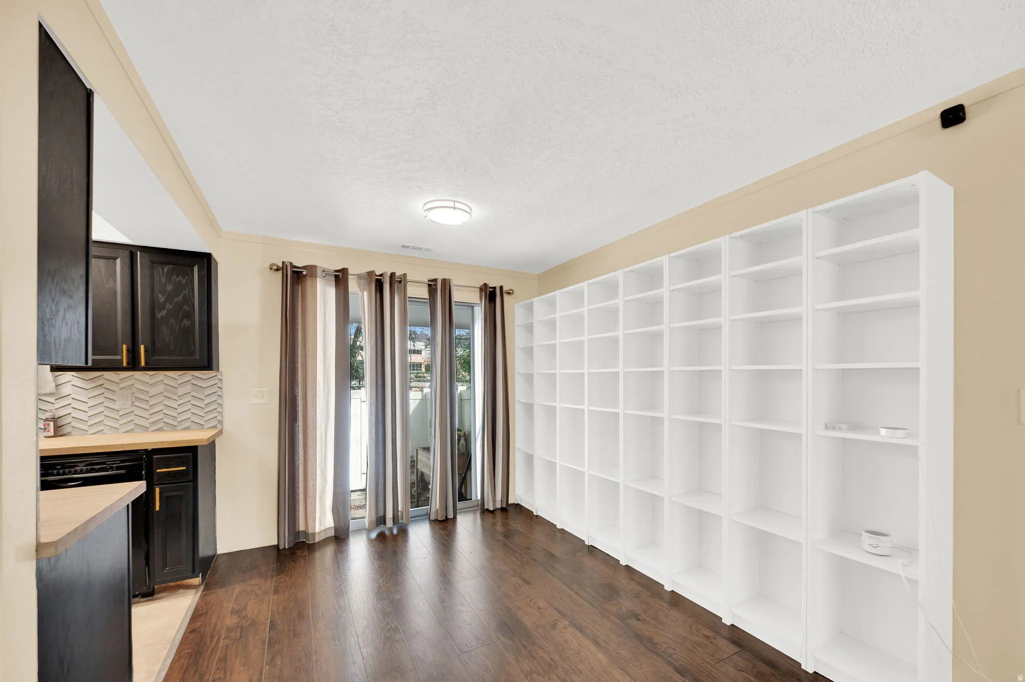 Unfurnished dining area featuring dark wood-style flooring and a textured ceiling