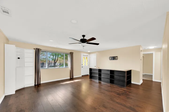 Unfurnished living room featuring dark wood finished floors, a ceiling fan, recessed lighting, and crown molding