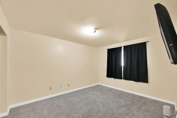 Carpeted spare room featuring a textured ceiling and baseboards