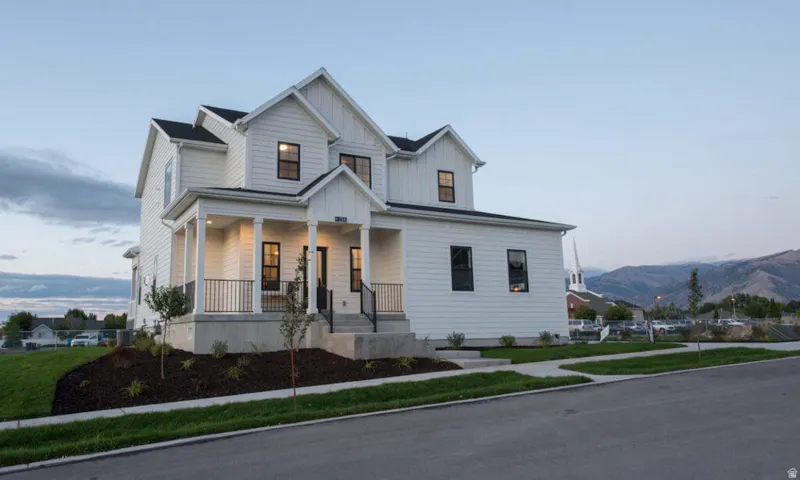 Modern farmhouse featuring board and batten siding, covered porch, and a front lawn