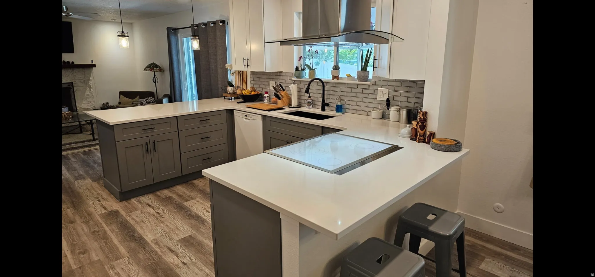 Two tone kitchen with a peninsula, a breakfast bar, range hood, a fireplace, and dual tone cabinetry