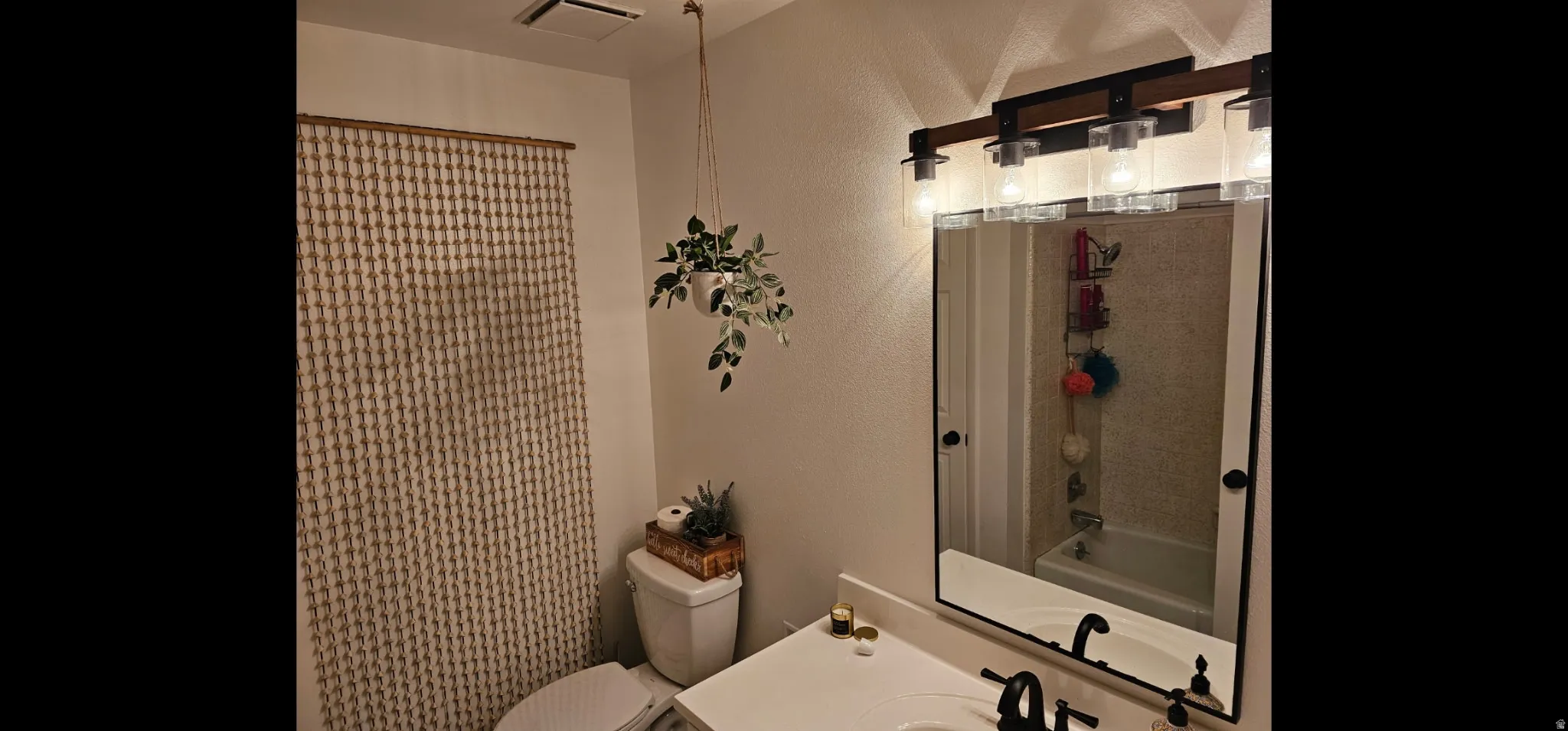 Full bath with a textured wall, vanity, and shower / tub combo