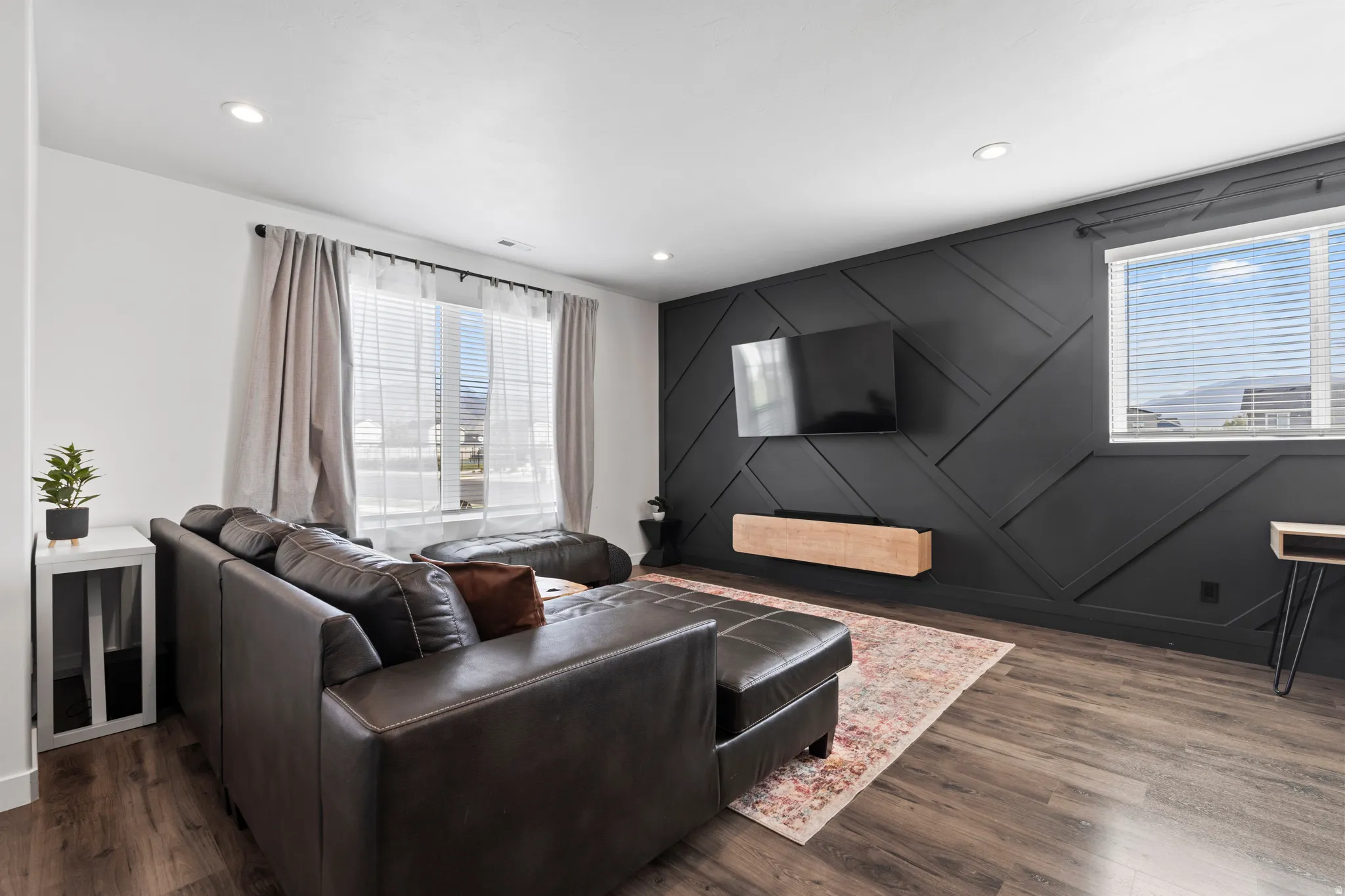 Living room featuring wood finished floors, a decorative wall, and recessed lighting