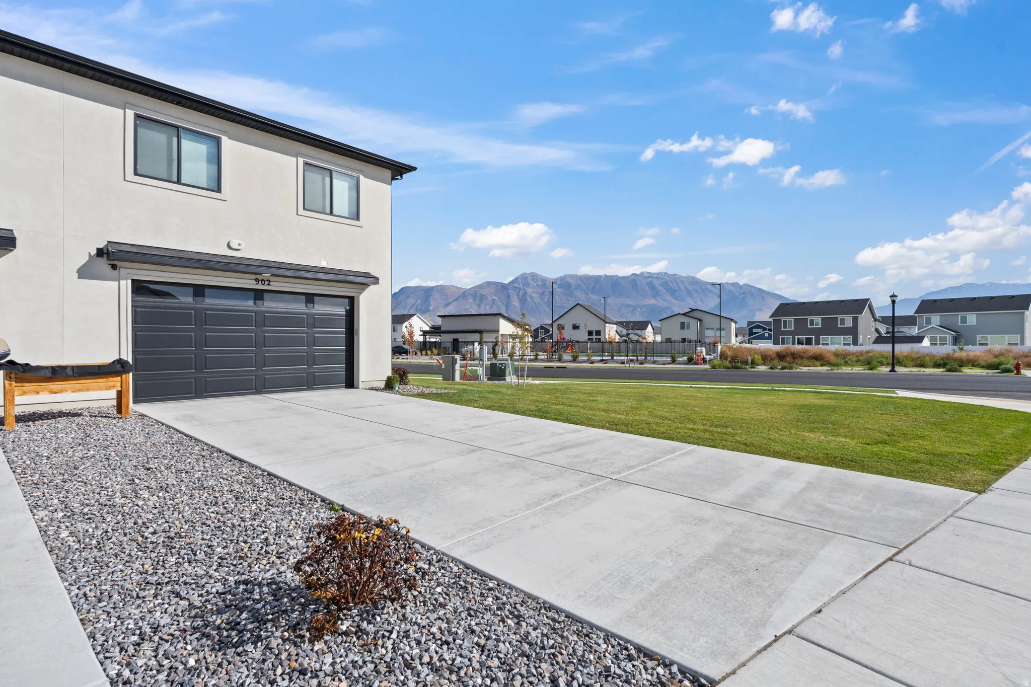View of side of property with driveway, stucco siding, a yard, and a garage