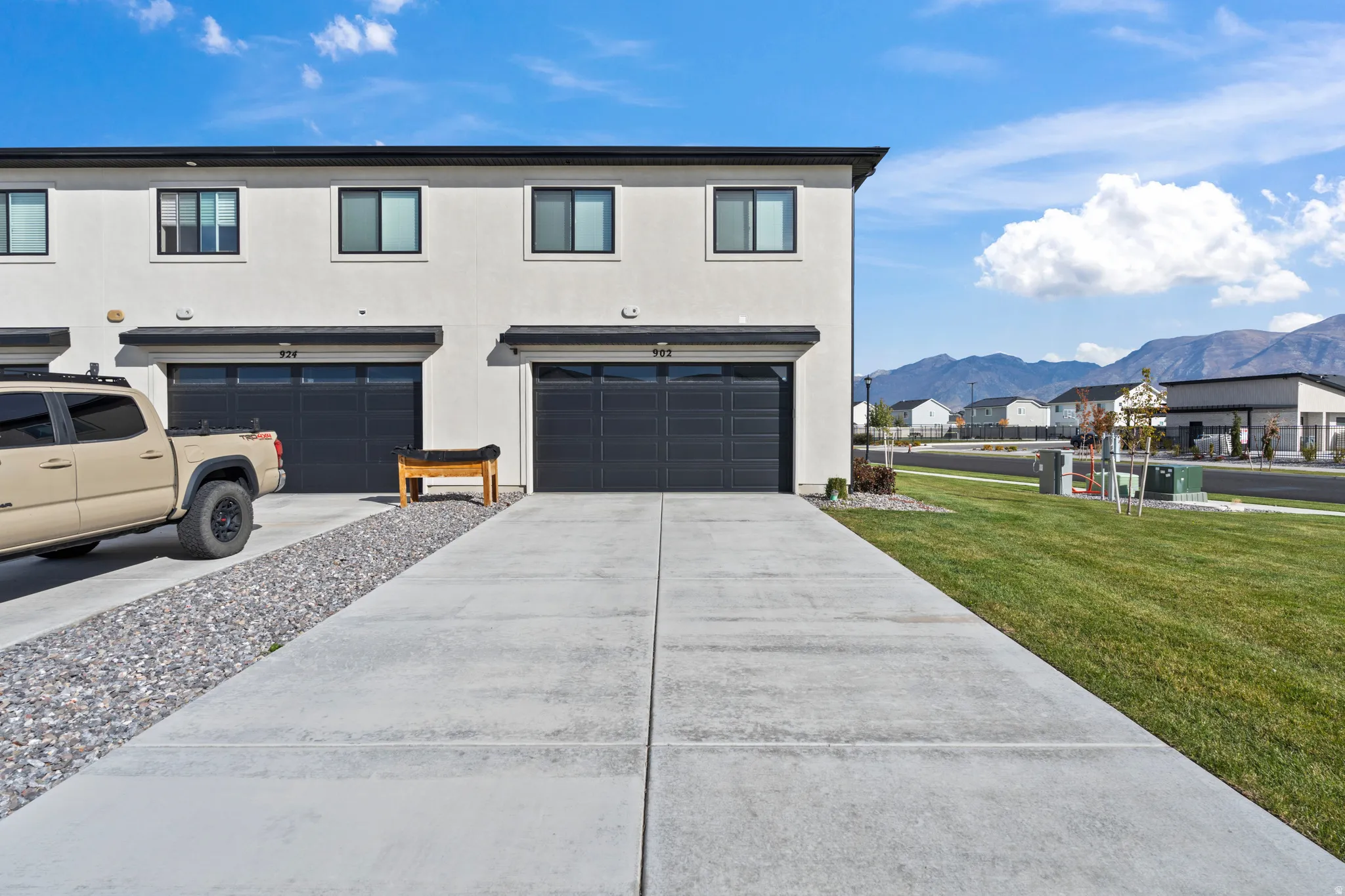 View of front of house with stucco siding, a garage, driveway, a front lawn, and a mountain view