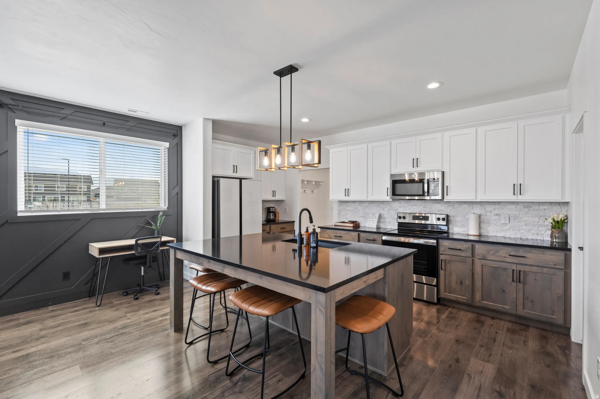 Kitchen with a kitchen bar, stainless steel appliances, dark wood-type flooring, a center island with sink, and dual tone cabinets