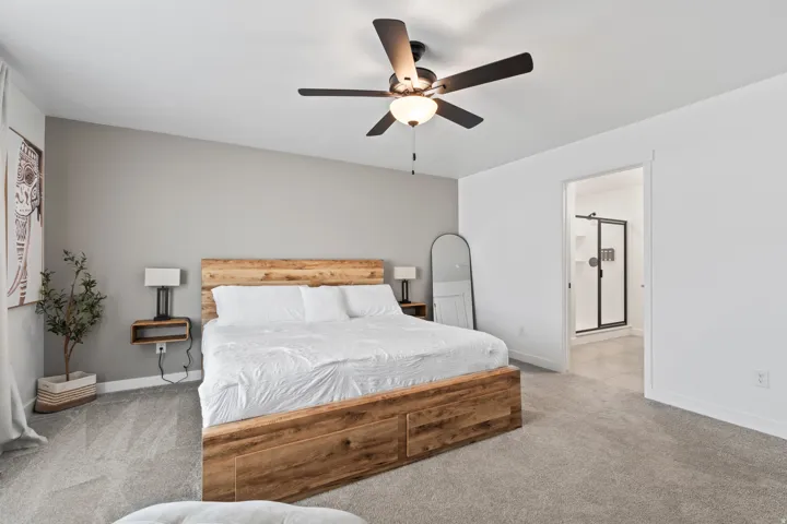 Bedroom featuring carpet, ensuite bathroom, and a ceiling fan
