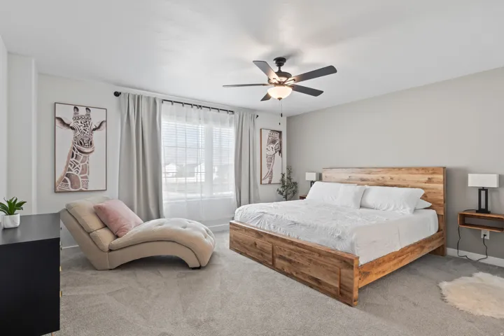 Carpeted bedroom featuring a ceiling fan and baseboards