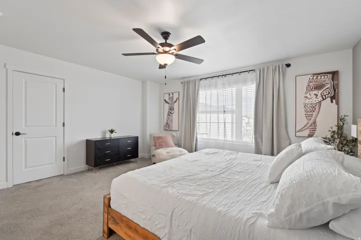 Carpeted bedroom with a ceiling fan and baseboards