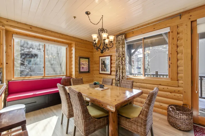 Dining room with suspended lighting, wood ceiling, rustic walls, and light wood-style flooring