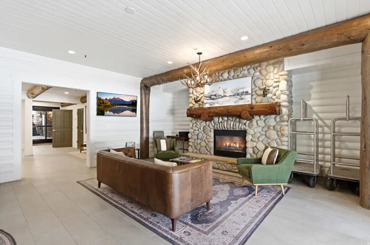 Living area featuring a chandelier, a fireplace, log walls, and beam ceiling