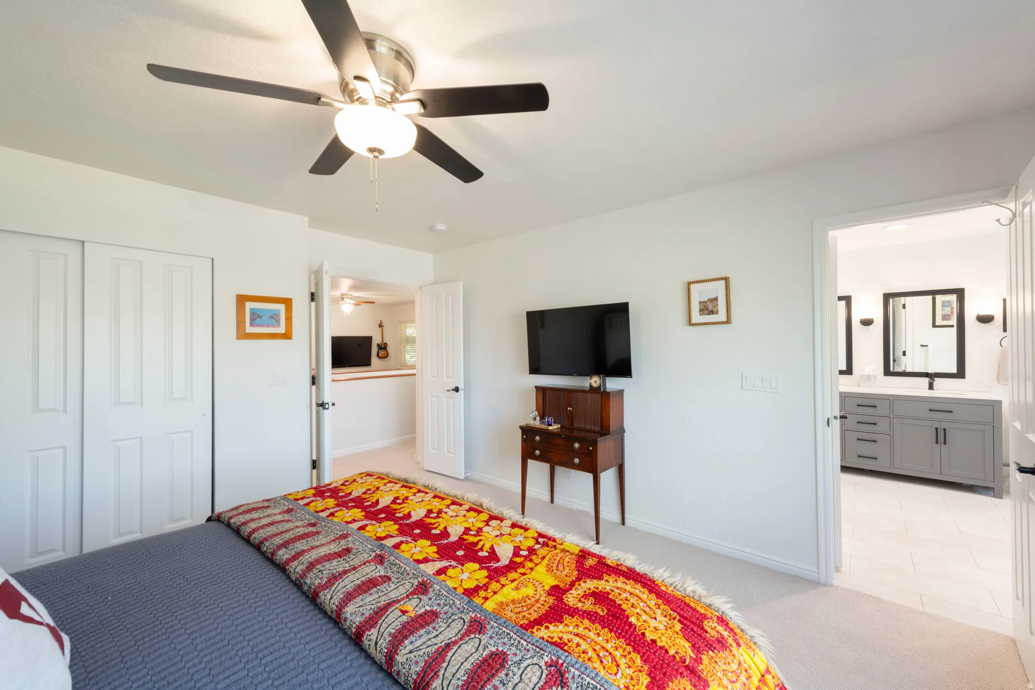 Bedroom featuring light carpet, connected bathroom, a ceiling fan, a closet, and light tile patterned floors