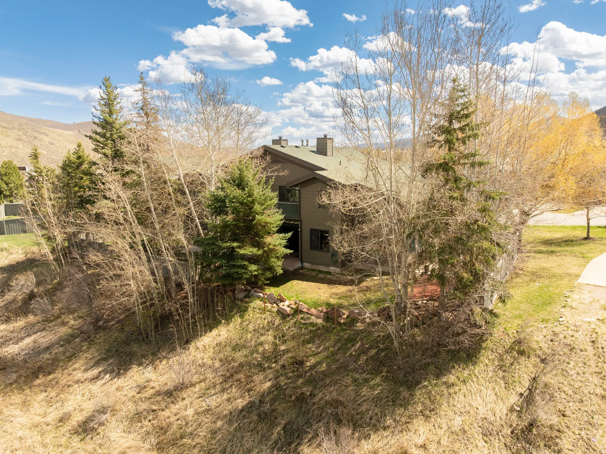 View of side of home with a lawn, a mountain view, a chimney, and a balcony