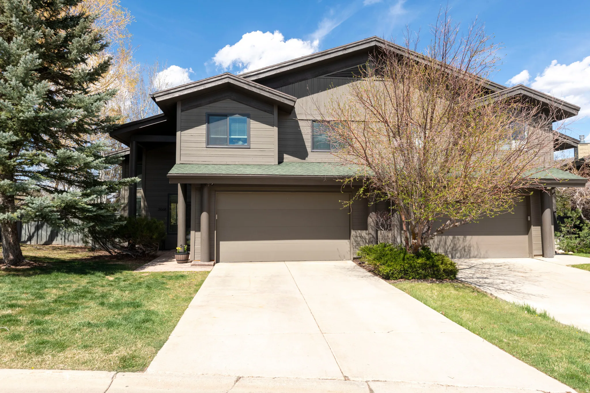 View of front facade featuring a garage, concrete driveway, and a front lawn