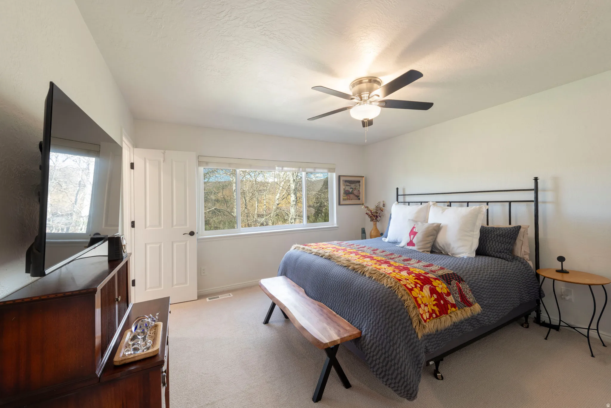 Carpeted bedroom with a ceiling fan and a textured ceiling