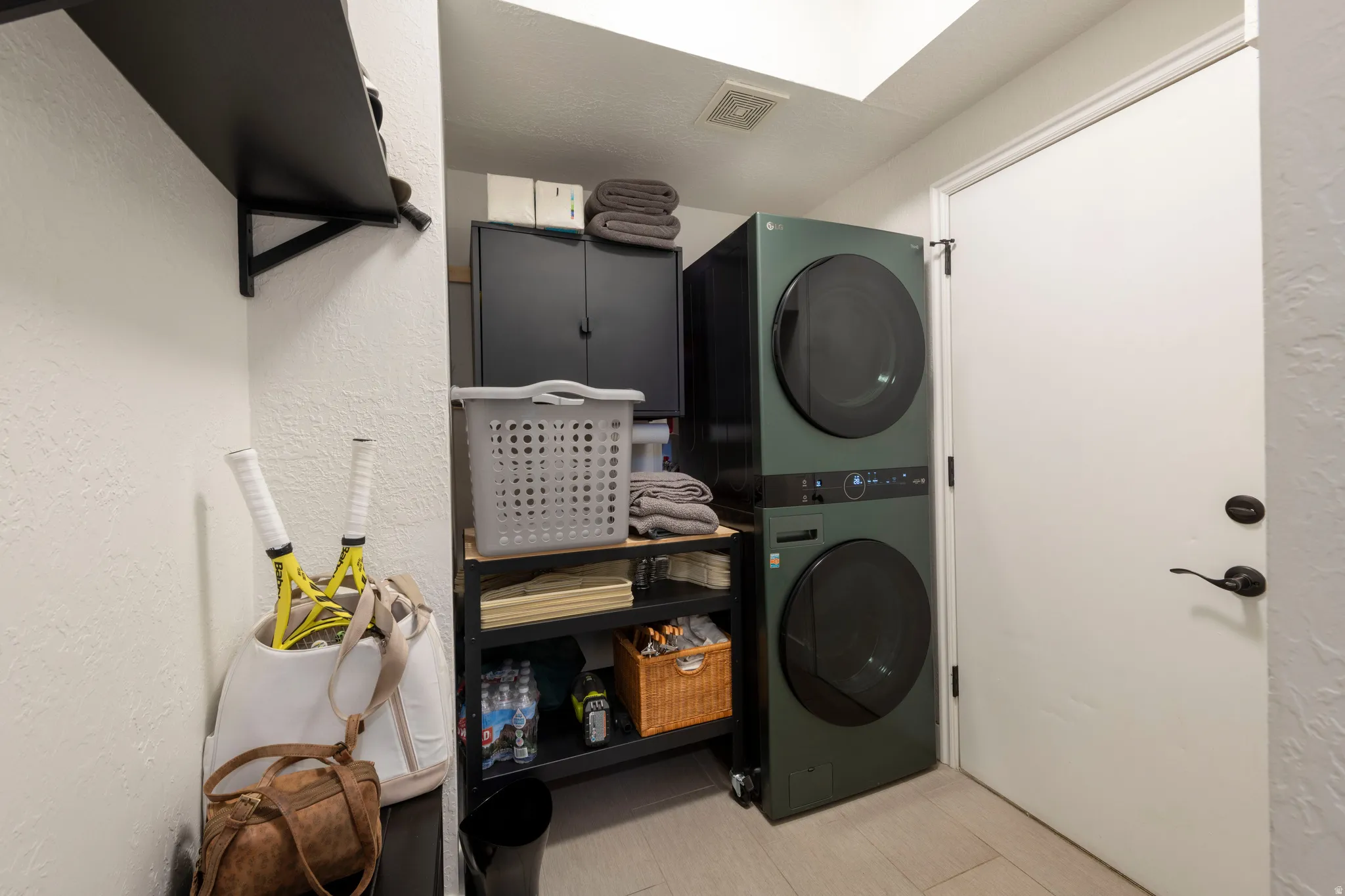 Laundry area featuring a textured wall and stacked washer and clothes dryer