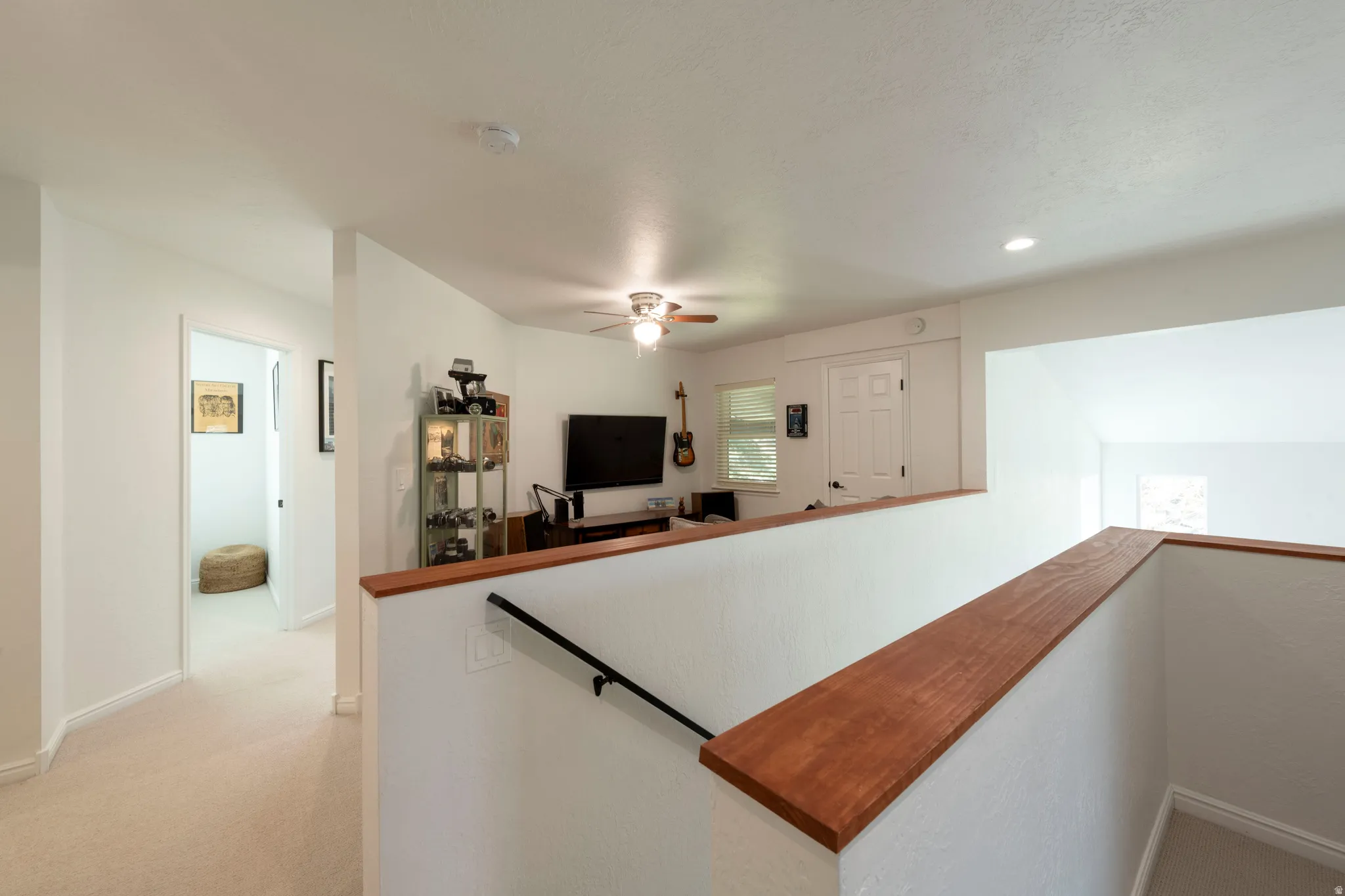 Hallway with an upstairs landing, light colored carpet, and recessed lighting