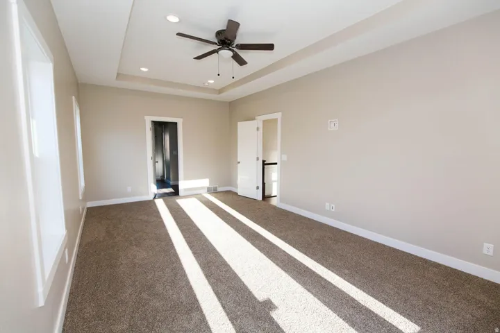 Unfurnished bedroom with carpet floors, recessed lighting, a ceiling fan, and a tray ceiling