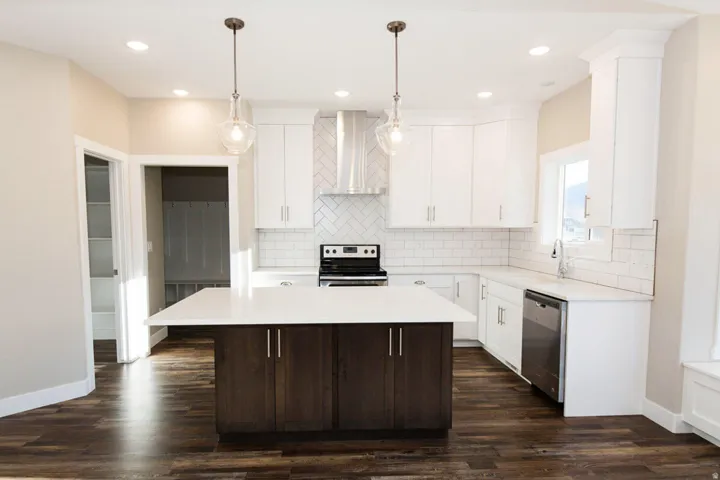 Two tone kitchen featuring stainless steel appliances, dark wood finished floors, dual tone cabinets, pendant lighting, and a kitchen island
